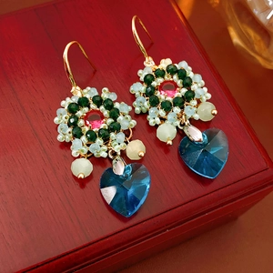 Dettaglio di orecchini vintage a fiore e cuore con cristallo blu su legno