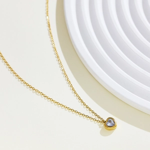 Detail view of 18k gold heart necklace featuring a light purple cubic zirconia stone