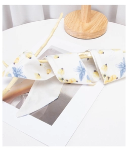 Detail of white long silk scarf with blue floral pattern wrapped on a wooden branch
