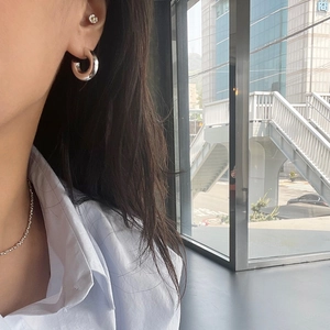 Close-up of modern silver hoop earrings and bead necklace on model in city setting
