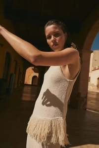 Dettaglio del vestito in maglia beige senza maniche con trama tessuta e orlo a frange