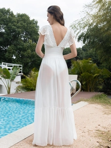 Detail of white fishnet lace beach dress featuring backless ruffle trim and sheer skirt