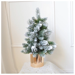 Close-up of mini snowy Christmas tree featuring a golden cylinder base and frosted needles