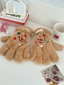 Gros plan de gants en peluche marron avec broderie de teckel et décor de Noël