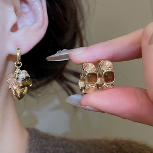 Detail view of heart tassels and square gemstones on gold tiger eye earrings