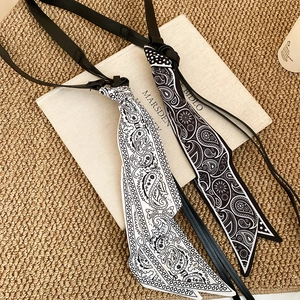 Détail de foulards en soie à motif cachemire noir et blanc avec accents de glands