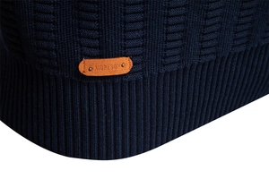 Close-up of brand logo patch and ribbed hem detail on dark blue striped sweater