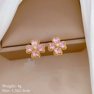 Detail of pink crystal heart clover earrings in gold frame on a brown jewelry box