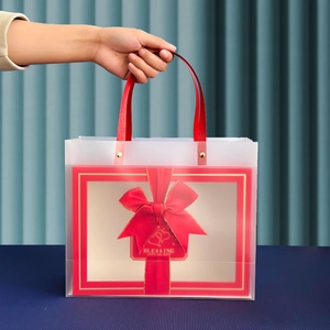 Frosted gift bag with red bow and gold Blessing tag held by hand for festive occasions