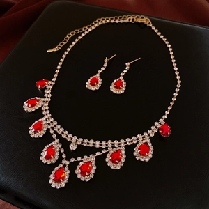 Detail of luxury gold necklace set featuring red teardrop gemstones and crystals