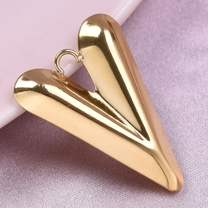 Polished gold heart pendant in stainless steel displayed on soft pink textured fabric