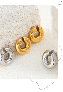 Macro detail of polished gold and silver C-shaped minimalist hoop earrings on white stone