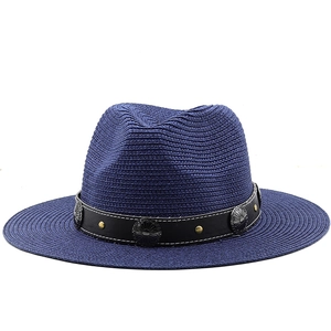 Detailed macro of a navy blue straw fedora with vintage buckle and metal studs