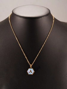 Detail of 18K gold hexagon pendant with blue shell inlay and letter A on black stand