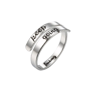 Close-up of adjustable stainless steel ring with keep going and fucking engravings