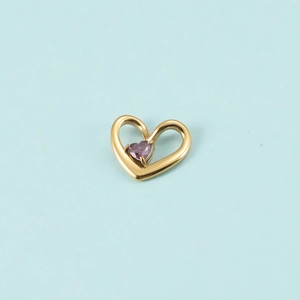 Gros plan d'un pendentif cœur doré serti d'une pierre violette sur fond bleu clair