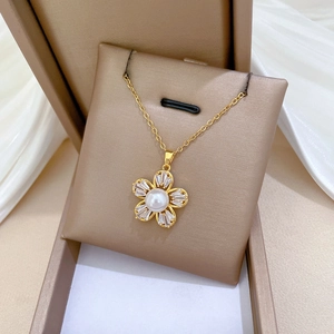 Detail of gold flower necklace with white pearl center and sparkling zircon petals