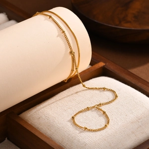 Detail of 18K gold-plated double-layer bracelet with sleek snake chain and beaded links
