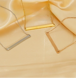 Gros plan sur trois colliers à barre minimalistes en acier inoxydable or, argent et rose