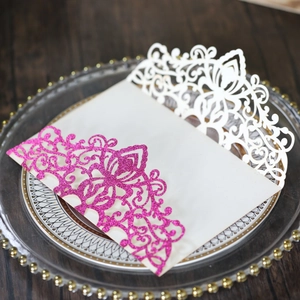 Detail of laser-cut hollow floral design on white and pink glitter wedding invitation cover