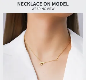 Close-up of gold paper plane and star charm necklace worn on a woman's neck