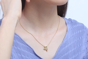Detail view of a gold rose pendant necklace on model with elegant snake chain design