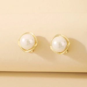 Detailed macro view of cream-colored pearl earrings with wave-textured gold frames