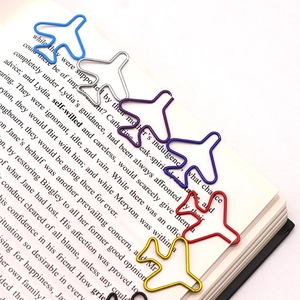 Macro shot of colorful airplane shaped metal paper clips attached to an open book page