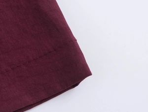 Macro shot of burgundy trousers showing fabric texture and neat stitching detail
