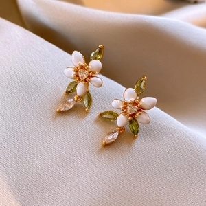 Detailed close-up of vintage flower earrings with white petals and green gemstones