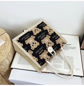 Detail of jute tote bag featuring cute cartoon bear print and natural wooden button closure