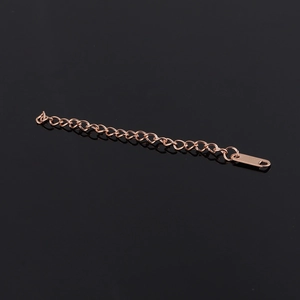 Macro shot of rose gold stainless steel extender chain with flat bar tag on black background
