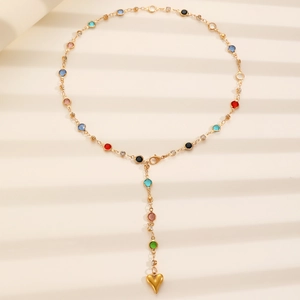 Detail of golden Y-shaped necklace with colorful stones and heart pendant on white background
