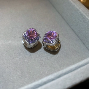 Macro view of silver earrings with purple crystals and pavé stones on grey velvet