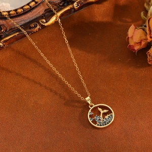 Detail of gold whale tail necklace with blue gemstone on vintage brown background