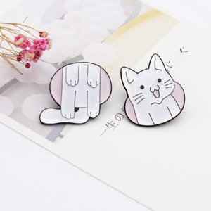 Close-up of a two-piece white cat enamel pin set showing a kitty hiding through a round hole