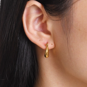 Detailed side view of water drop crescent gold earrings worn on ear with polished finish