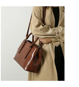 Close-up of brown polished leather tote bag with dual straps and elegant gold logo detail
