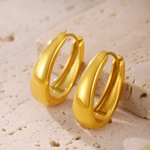 Polished gold-plated teardrop hoop earrings on beige limestone base for a luxury look
