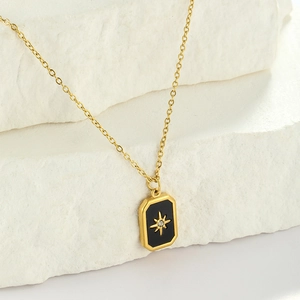 Detail of gold starburst necklace with black enamel pendant and zircon inlay