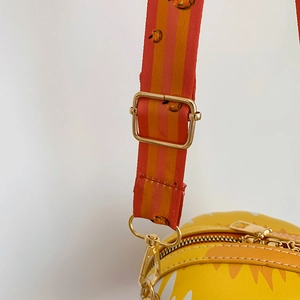 Detail of adjustable orange stripe fabric strap with gold metal hooks and pumpkin pattern