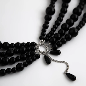 Detail of multi-layer body chain with black beads and silver metal clasp connectors
