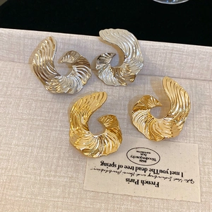 Detailed view of gold and silver irregular spiral earrings with textured metal finish