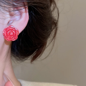 Detail shot of a red rose stud earring with 3D sculpted petals on a model's ear lobe