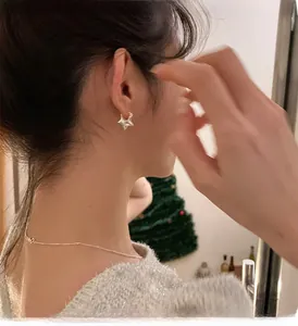 Dettaglio di un orecchino a stella in argento sterling 925 indossato da un modello