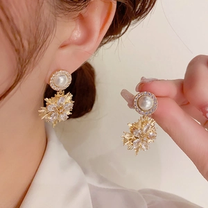 Detail showing elegant gold firework drop earrings with pearls and crystals on a model