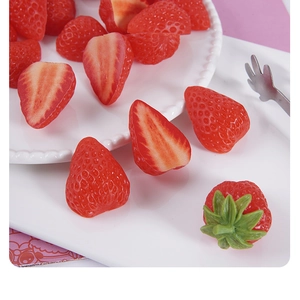 Realistic PVC strawberry slices and whole fake fruits displayed on a ceramic plate