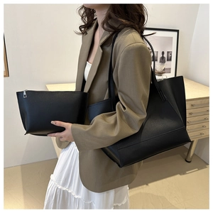 Detail of black matte leather tote bag and pouch set held by a model in a lifestyle scene