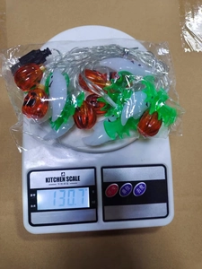 Detailed view of Halloween LED string lights being weighed on a digital scale for accuracy