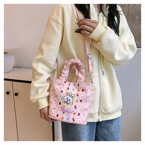 Detail of pink canvas bucket bag featuring a cartoon rabbit and ruffled handle on a model